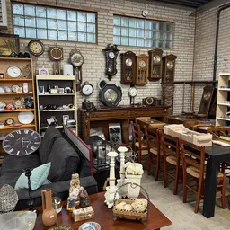 Interieur van kringloopwinkel met klokken, servies, meubels en verzamelobjecten op stellingen en tafels