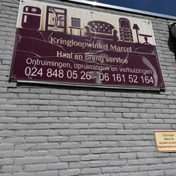 Gevel van bakstenen muur met bordeauxrood winkelnaambord en tekst over diensten en telefoonnummers