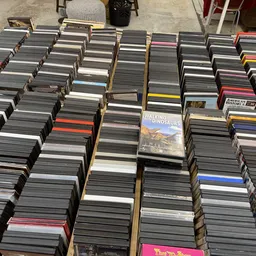 Grote verzameling cd's en dvd's uitgestald in dozen op de grond van de winkel