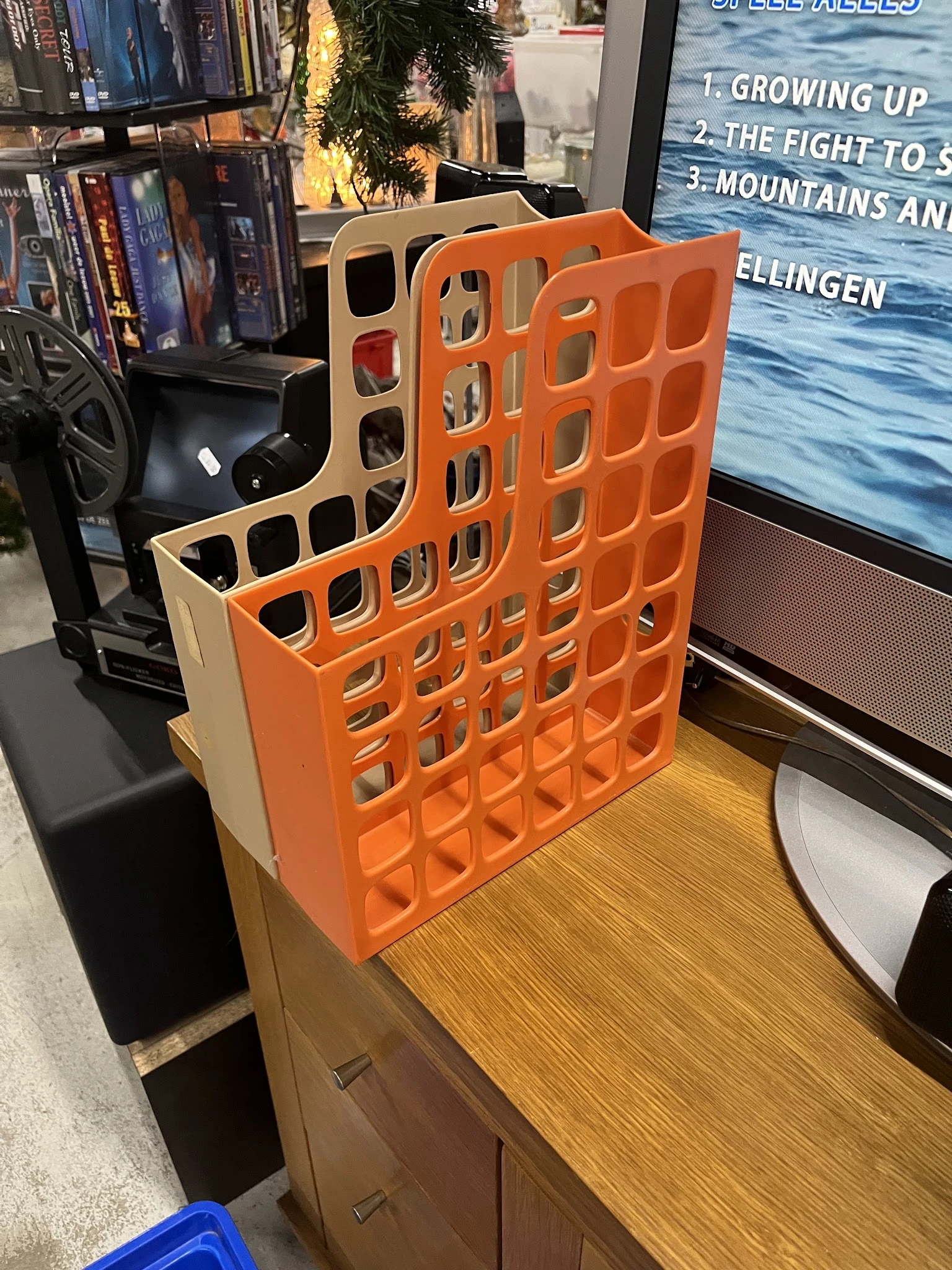 Oranje kunststof organizer met vierkante vakken, staand op houten oppervlak in winkel