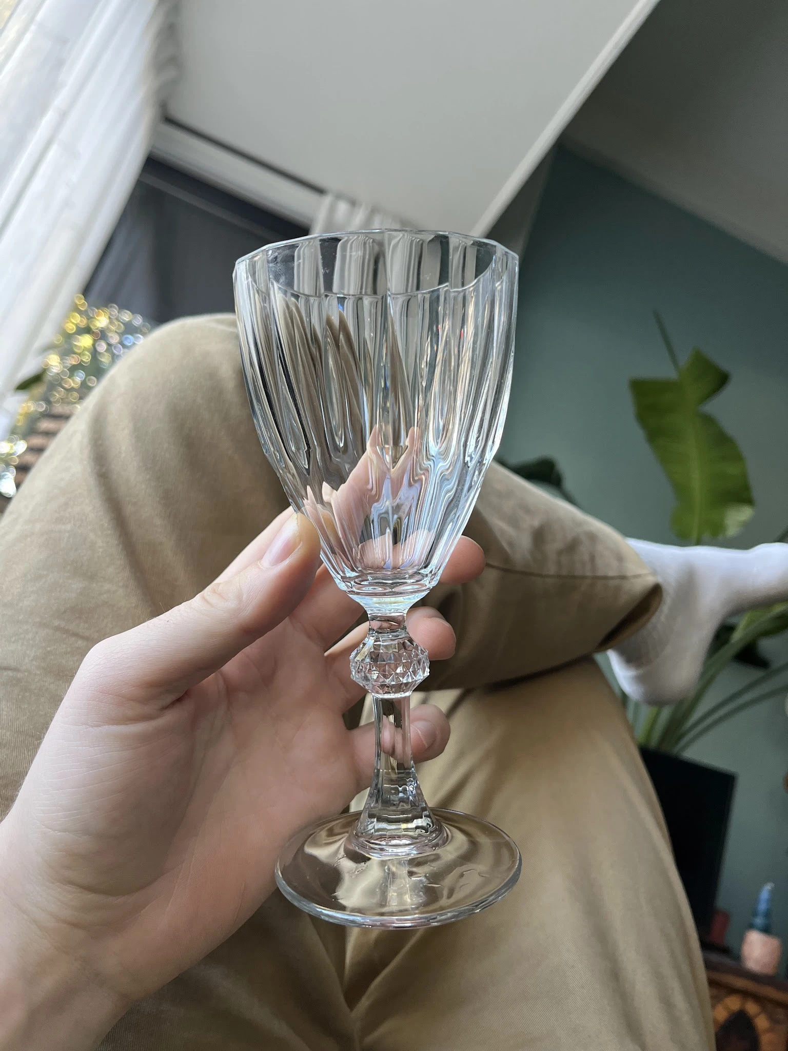 Close-up van een kristallen wijnglas met geribde structuur, gehouden in een hand