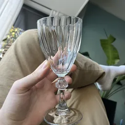 Close-up van een kristallen wijnglas met geribde structuur, gehouden in een hand