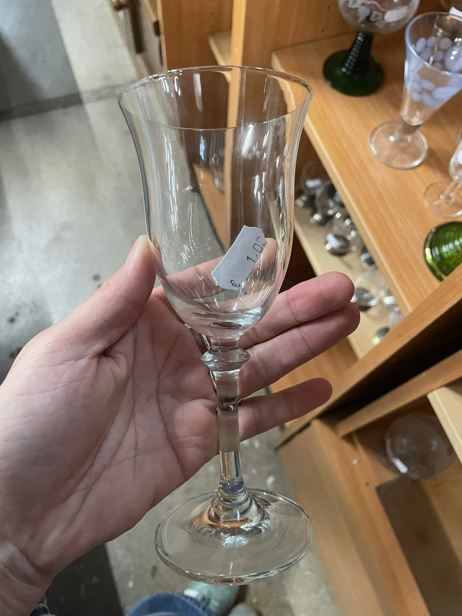 Hand houdt een leeg wijnglas vast met een prijskaartje eraan
