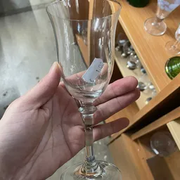 Hand houdt een leeg wijnglas vast met een prijskaartje eraan