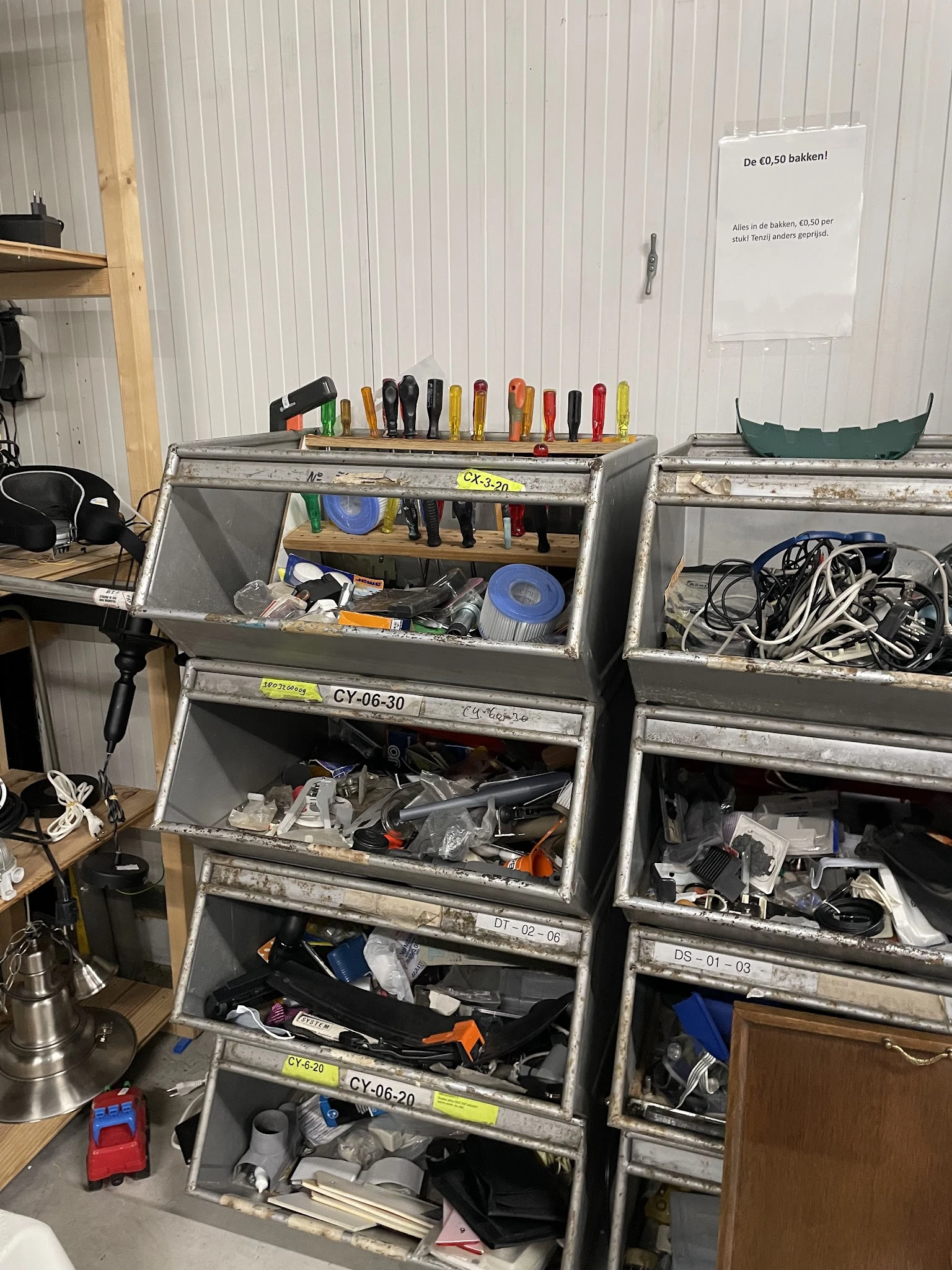 Metalen opbergbakken gevuld met gereedschap, elektrische kabels en diverse huishoudelijke artikelen