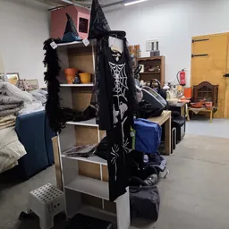 Halloweendecoratie met zwarte kasten, spinnenwebben en skeletpoppen tussen ander meubilair in de winkel