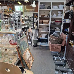 Winkelinterieur met boekenkasten, manden, glazen servies en diverse tweedehands artikelen