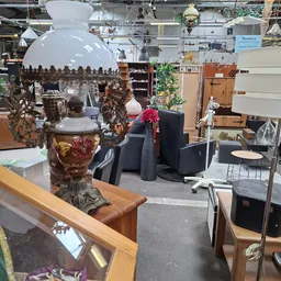 Winkelvloer met decoratieve voorwerpen, meubels en huisraad uitgestald, grote hanglamp zichtbaar