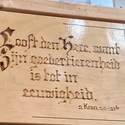 Houten plank met verbrand/gebrande tekst in gotisch schrift, mogelijk een decoratief wandpaneel