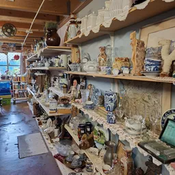 Stellingen vol met antieke serviesgoed, porselein, vazen en decoratieve voorwerpen in een kringloopwinkel