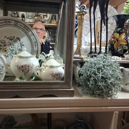 Vitrinekast met porselein serviesgoed en decoratieve items in een kringloopwinkel