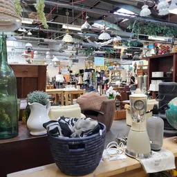 Binnenaanzicht van kringloopwinkel met uiteenlopende tweedehandsartikelen: meubels, decoratie, lampen, huisraad en textiel op