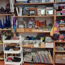 Houten stellingen en witte bakken met uiteenlopende spullen zoals boeken, kandelaars, wollen ballen en decoratieve items