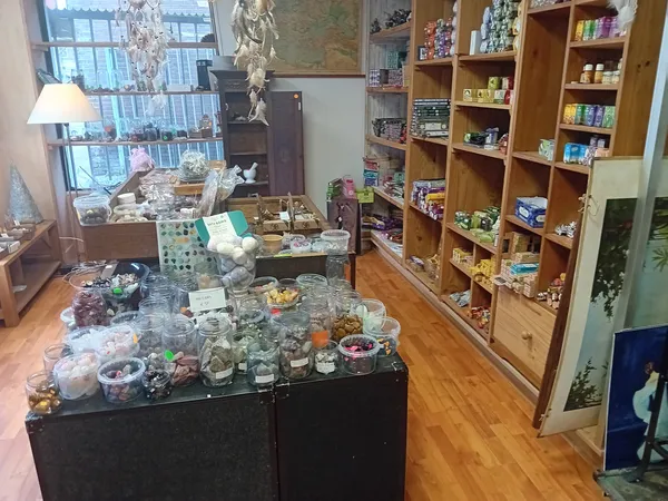 Winkelbinnenruimte met vitrinekast vol collectibles, boekenkasten en uitzicht op straat via raam