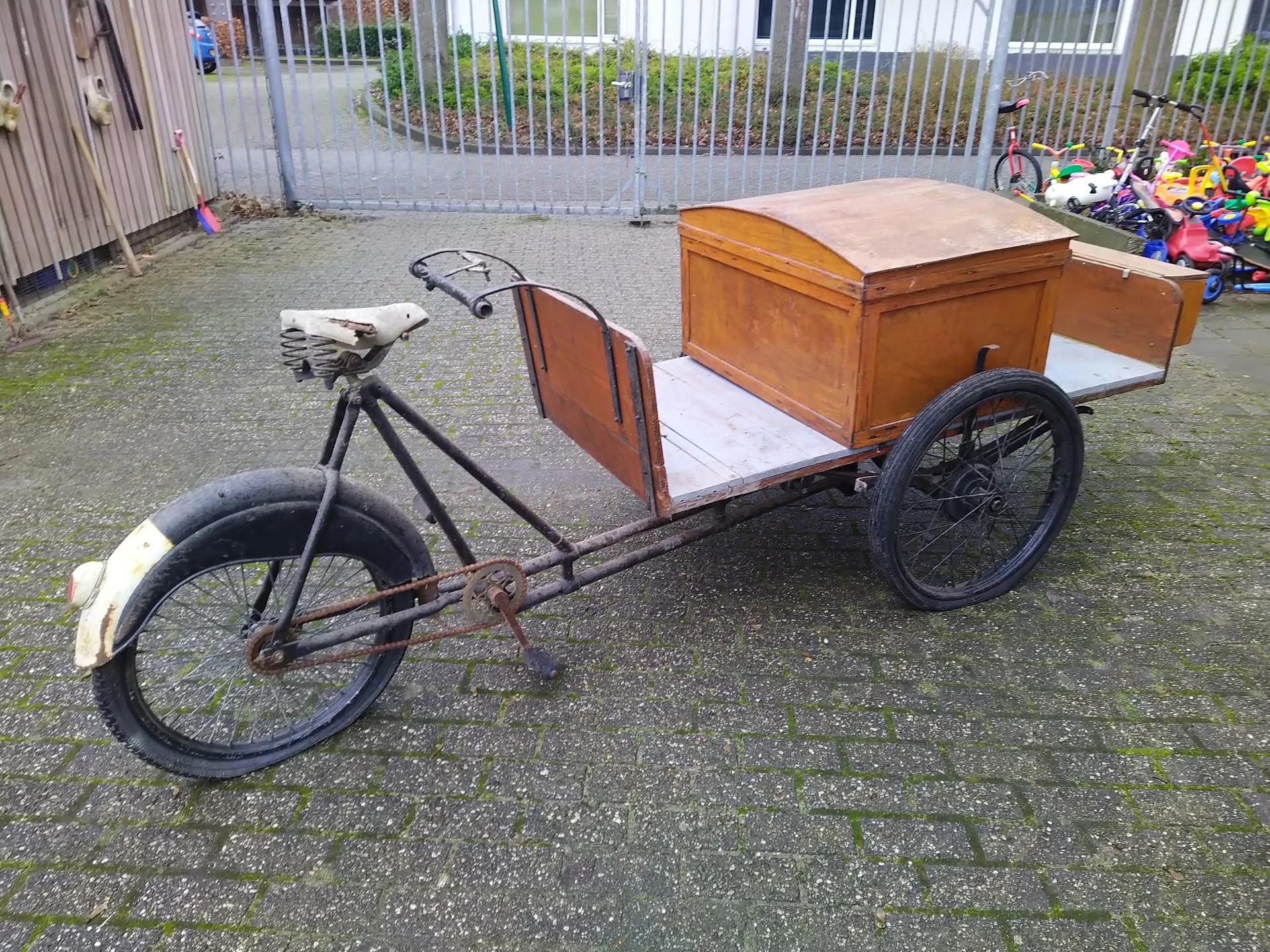 Antieke bakfiets met houten laadkist op wielen in een kringloopwinkel