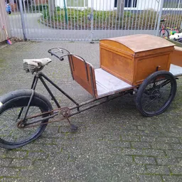 Antieke bakfiets met houten laadkist op wielen in een kringloopwinkel