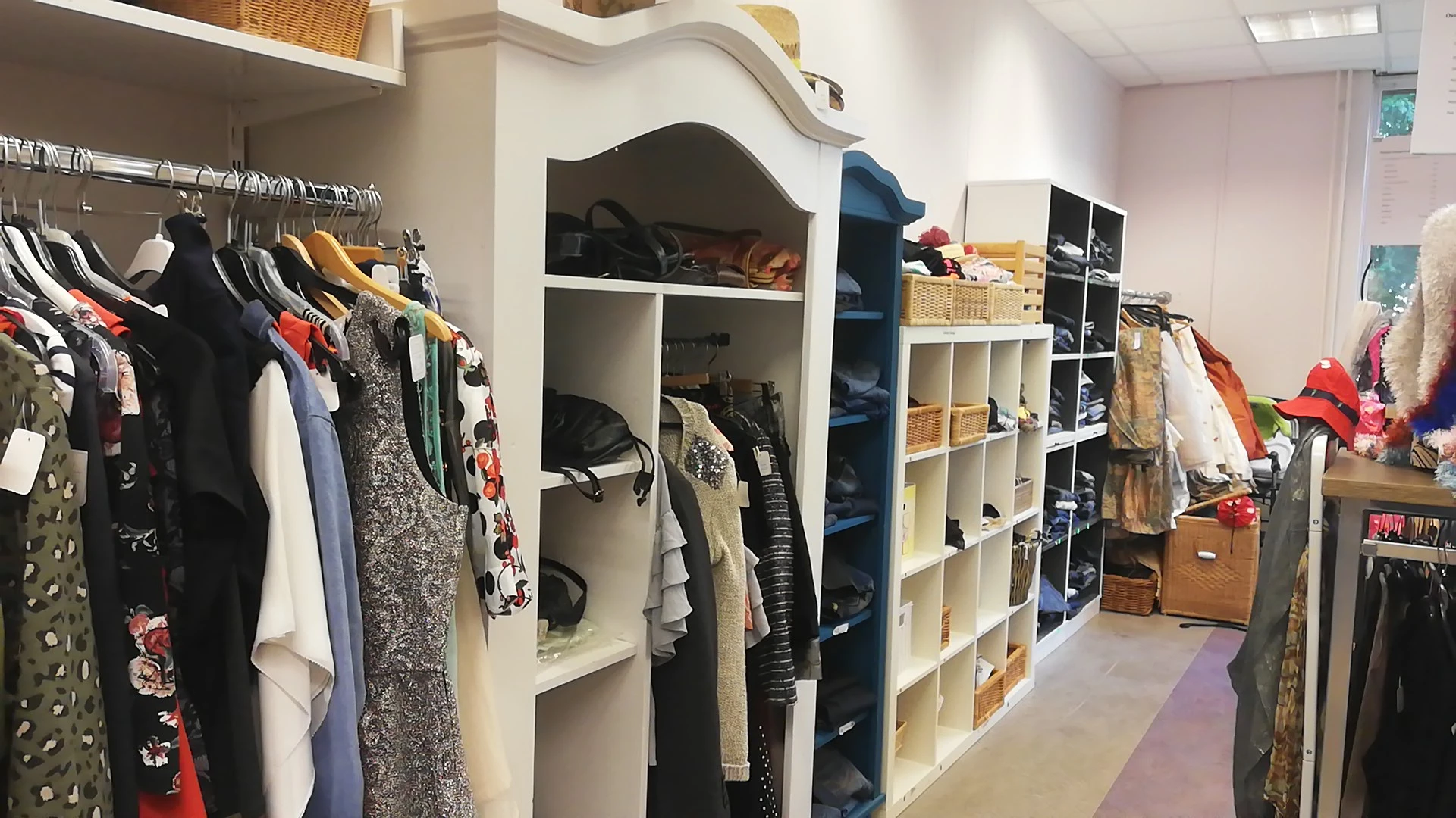 Winkelinterieur met kledingrekken, stellingen en opbergvakken vol tweedehands kleding en accessoires