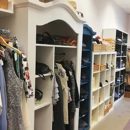 Winkelinterieur met kledingrekken, stellingen en opbergvakken vol tweedehands kleding en accessoires