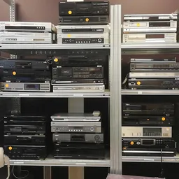 Stellingen met tweedehands audio- en elektronicaapparatuur, waaronder versterkers, tuners en andere stereocomponenten