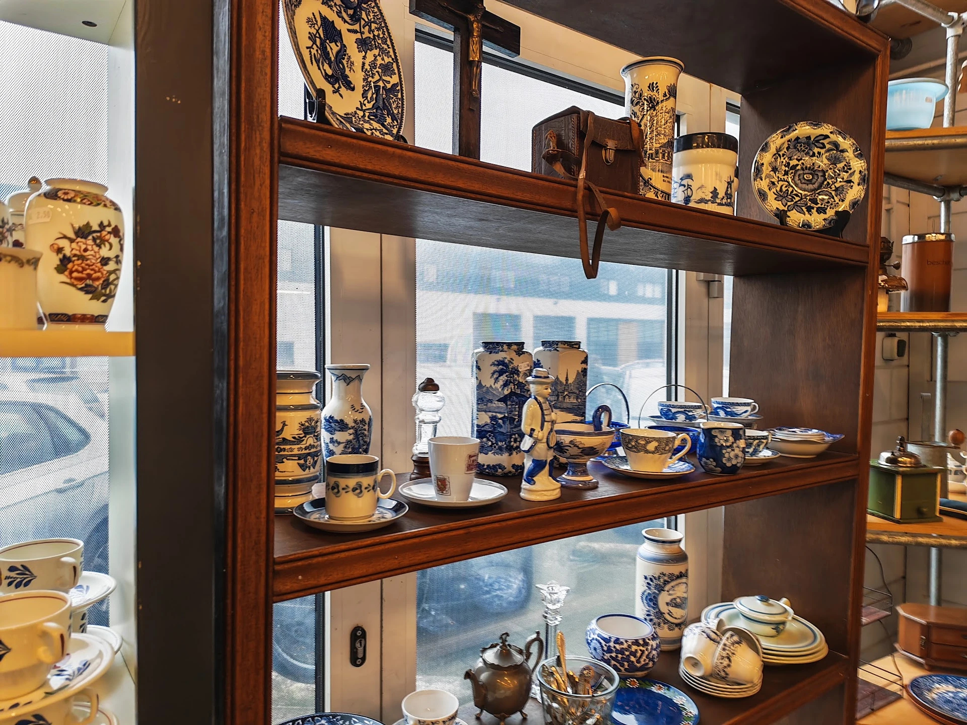 Glazen vitrinekast met antieke gele en blauwe porseleinen serviesgoed en decoratieve objecten