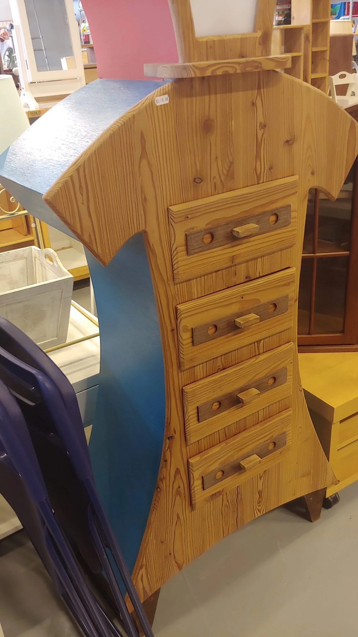 Houten ladekast met vier laden en ronde knopjes, schuin opgesteld in de winkel
