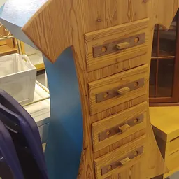 Houten ladekast met vier laden en ronde knopjes, schuin opgesteld in de winkel