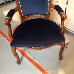 Houten fauteuil met donkerblauwe fluweelbekleding en koperen siernagels, van bovenaf gefotografeerd