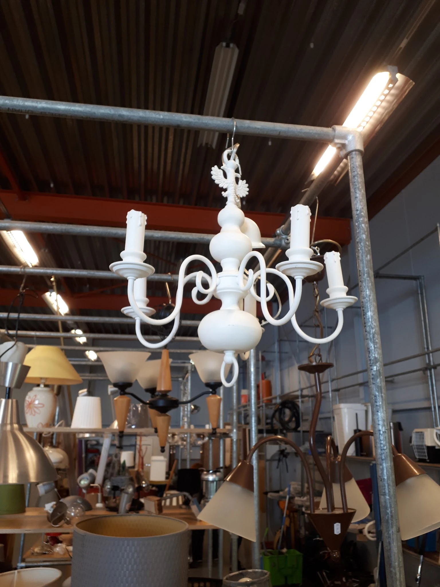 Witte kroonluchter met zes armen en kaarsen, hangend in de winkel