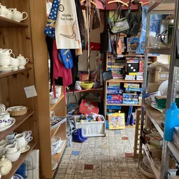 Binnenaanzicht van kringloopwinkel met rekken boeken, speelgoed, kleding en huishoudartikelen