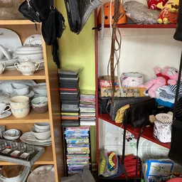 Stellingen met servies, dvd's, speelgoed en huishoudartikelen in een kringloopwinkel