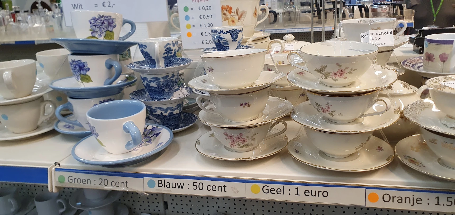 Uitgestalde serviesgoed met kopjes, schotels en kannen in blauw-wit en bloemenmotief met prijskaartjes