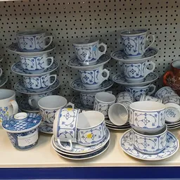 Uitgestalde serviesgoed met blauw-wit porselein kopjes, schotels en borden op een stellage