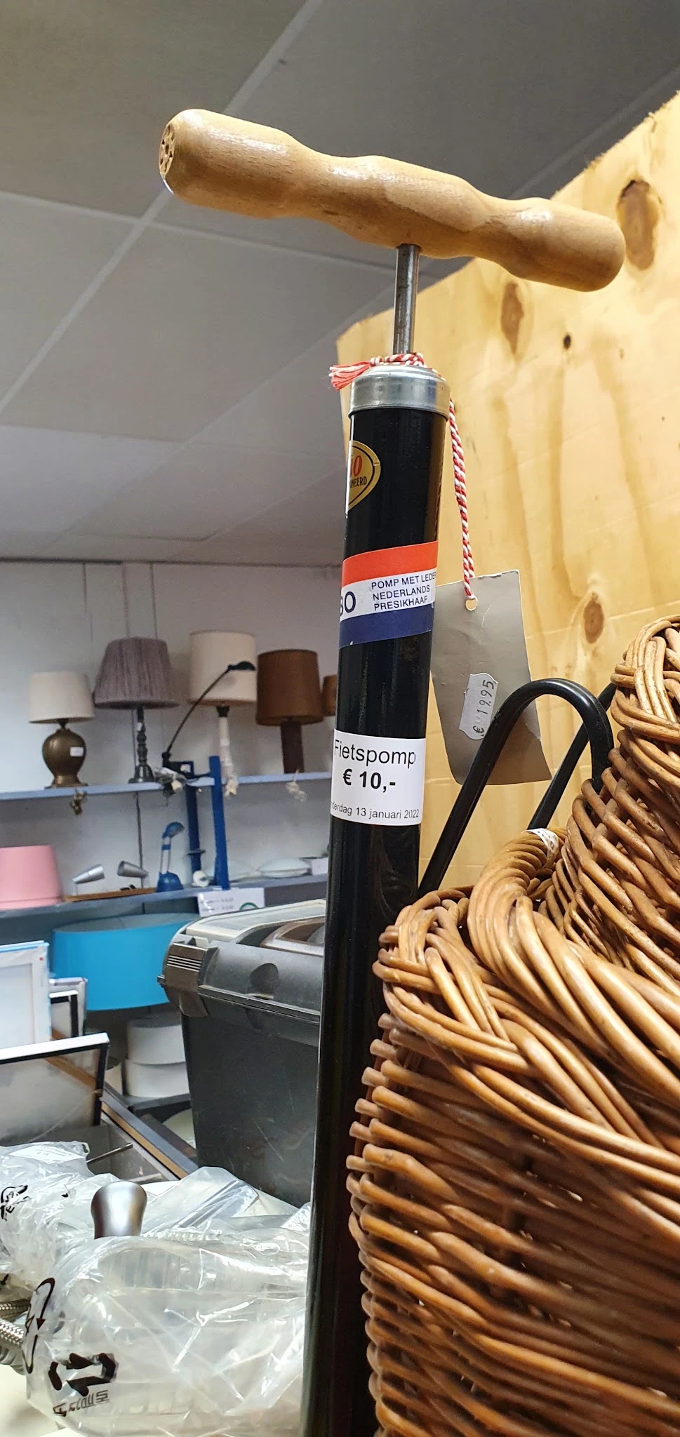 Close-up van een decoratieve zwarte fles met Nederlands etiket en een stroparaplu, tegen achtergrond met lichten en huishoude
