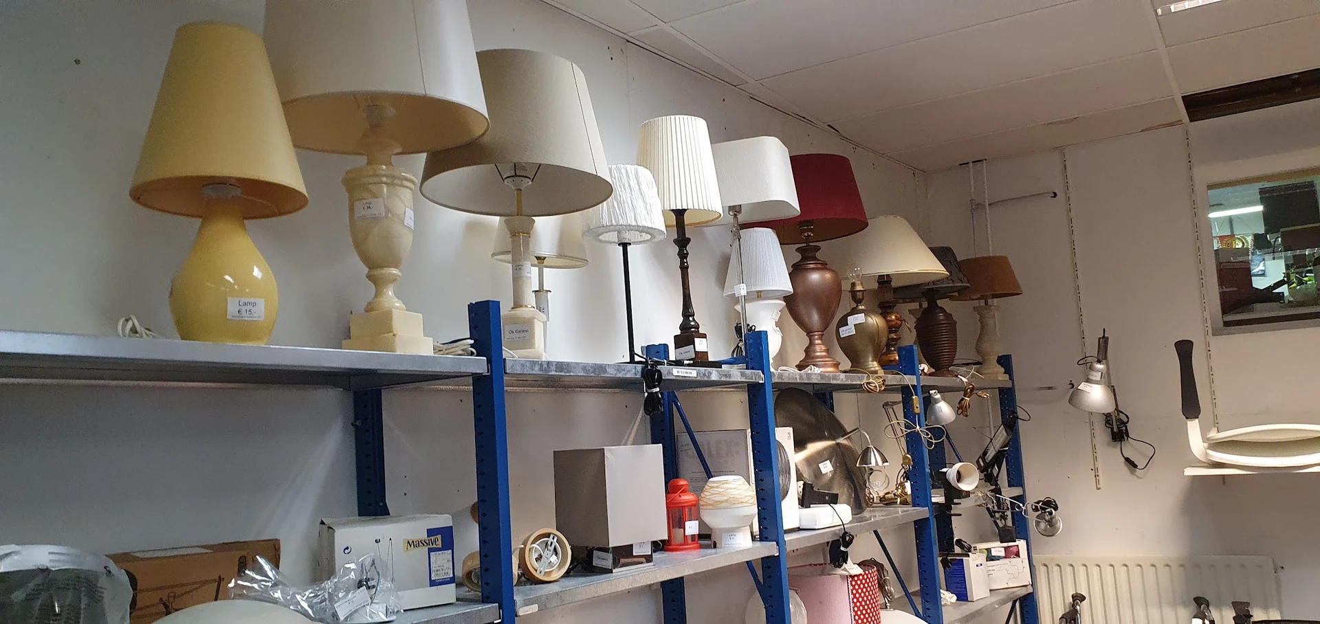 Blauwe stellingen met diverse tafellampjes en lampenkappen in verschillende stijlen en kleuren