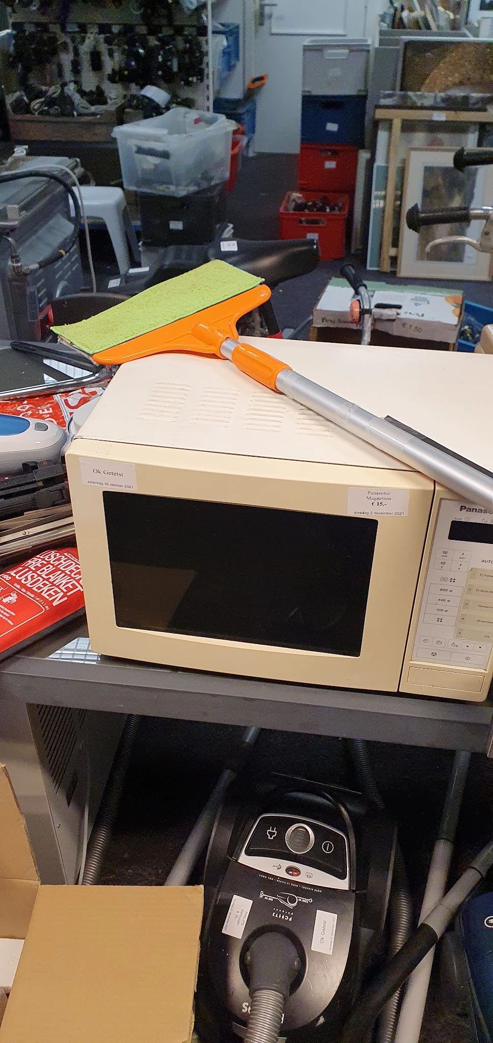 Vintage OKi Datasu magnetron met oranje handvat op werkblad tussen ander gebruikte huishoudapparatuur