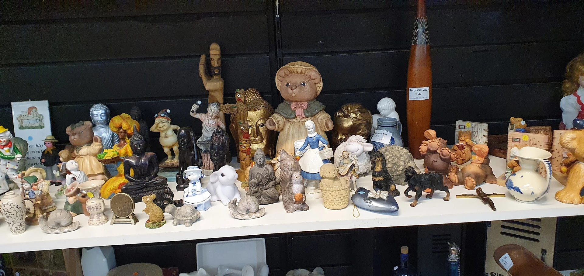 Verzameling van beeldjes, speelgoed en decoratieve objecten op een witte tafel tegen zwarte achtergrond
