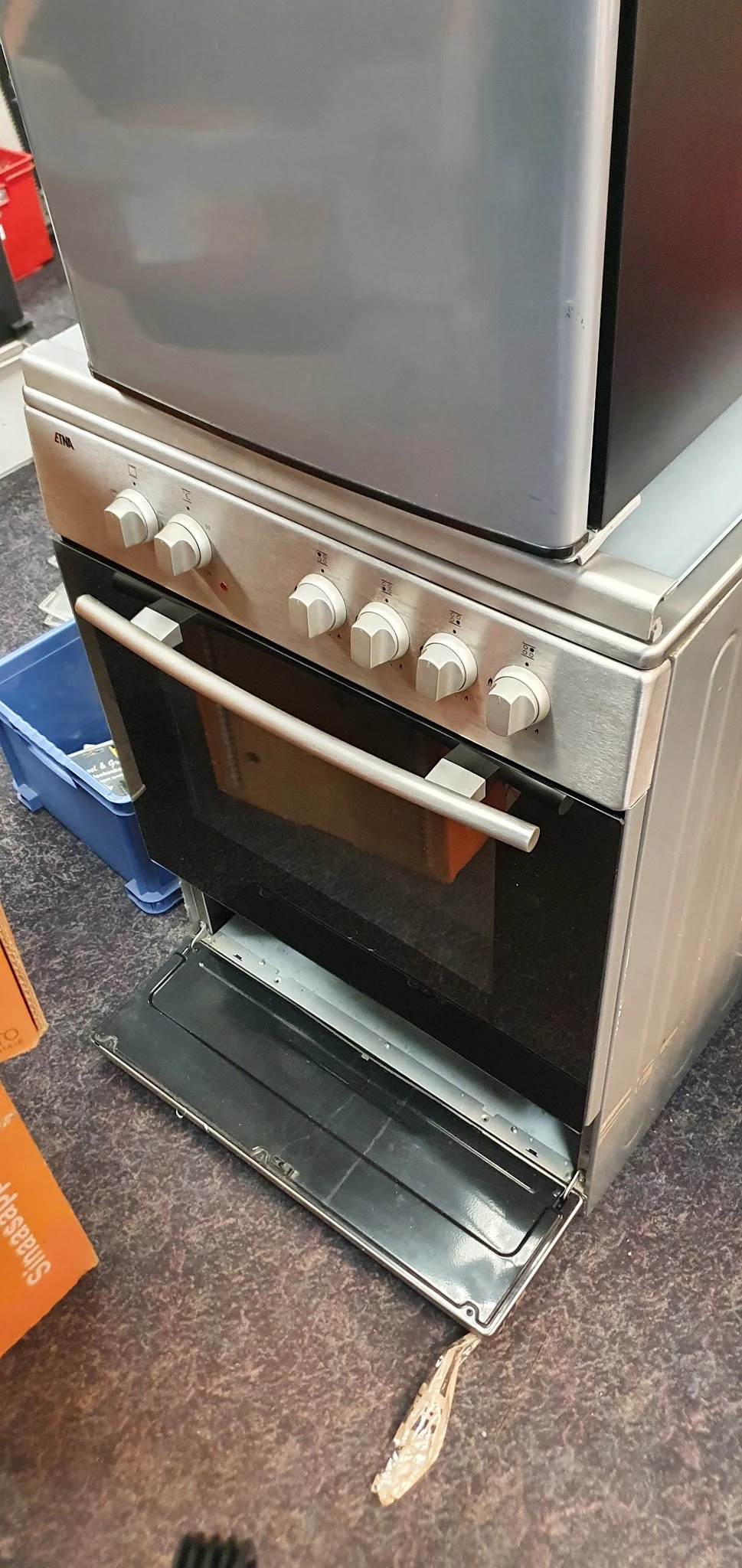 Vrijstaande gasfornuis met oven in rvs/zilver, geopend deurtje, witte bedieningsknoppen bovenaan