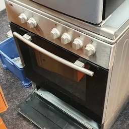 Vrijstaande gasfornuis met oven in rvs/zilver, geopend deurtje, witte bedieningsknoppen bovenaan