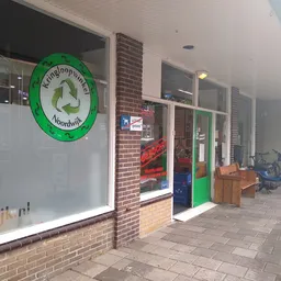 Winkelfront met groene deur, bakstenen gevel en groot groen rond logo met recyclesymbool
