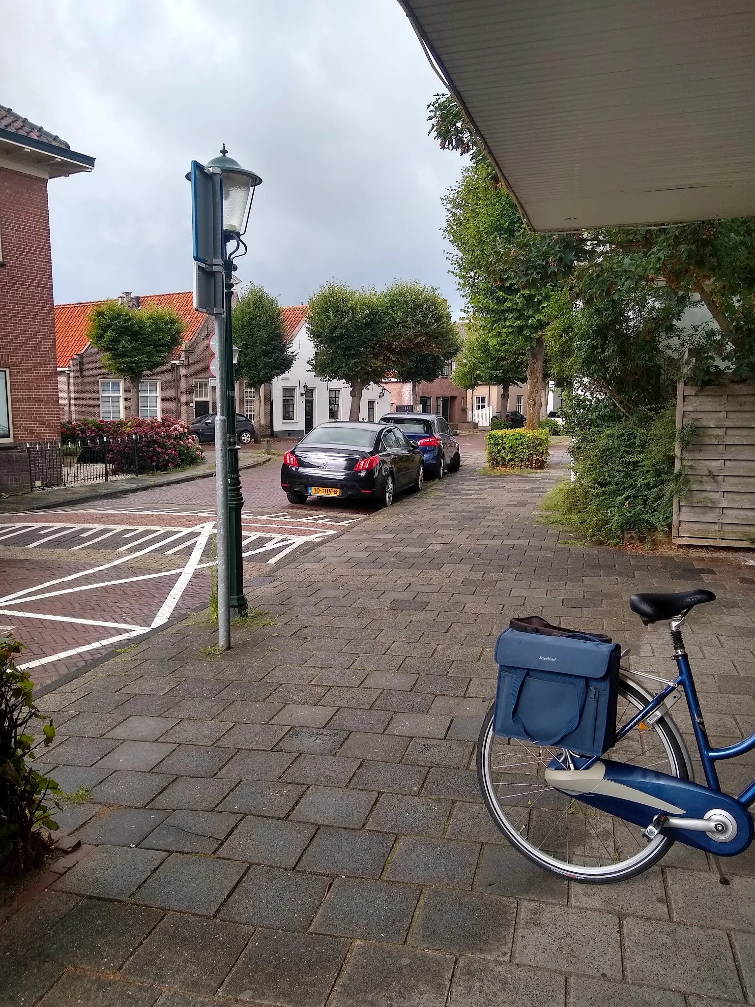 Straatgezicht met geparkeerde auto's en fietsen voor een rij gebouwen