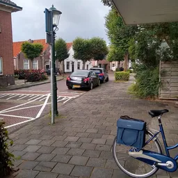 Straatgezicht met geparkeerde auto's en fietsen voor een rij gebouwen