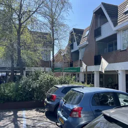 Voorgevel van kringloopwinkel aan Marktplein met parkeerplaatsen en geparkeerde auto's ervoor