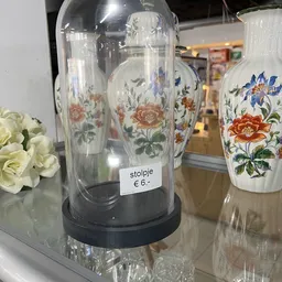 Glazen vaas met bloemendecoratie en prijskaartje van 6 euro, naast witte bloemen