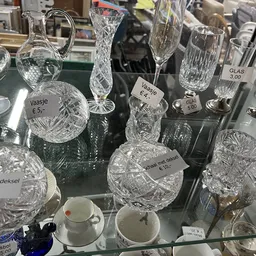 Vitrinekast met kristallen glazen, kannen en serviesgoed met prijskaartjes