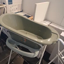 Grijze babybadkuip op wit onderstel met opbergvak