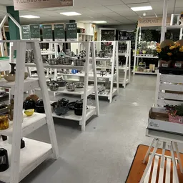 Winkelvloer met witte stellingen vol huishoudelijke artikelen, servies en keukengerei
