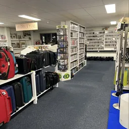 Winkelinterieur met stellingen vol cd's en dvd's, koffers en tassen op display, en een muziek- en filmafdeling