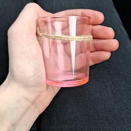 Hand met roze/rood glas met water en touw eraan