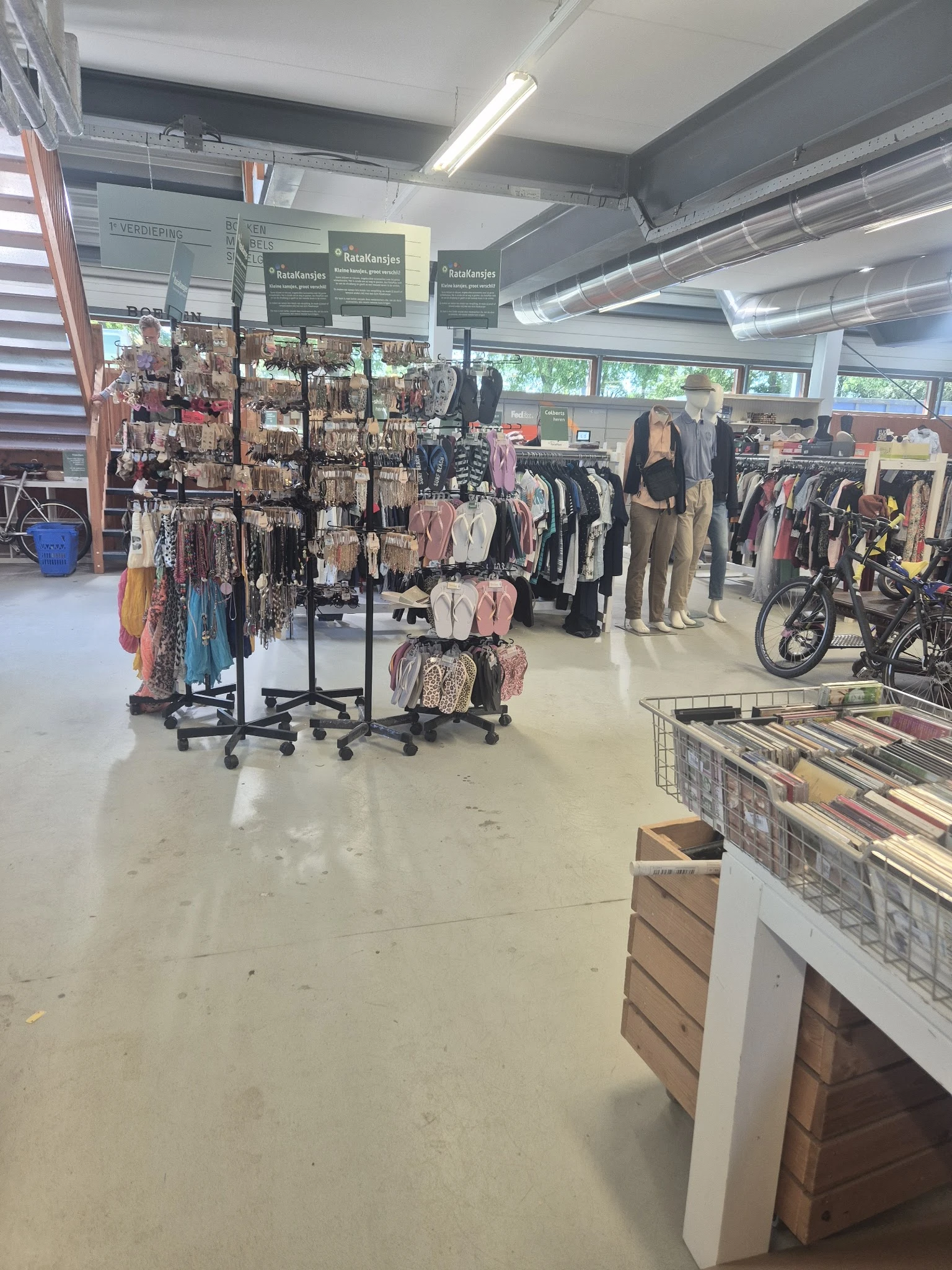Winkelvloer met kledingrekken, mannequins en fietsen in kringloopwinkel