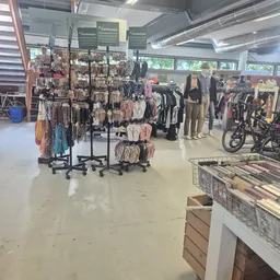 Winkelvloer met kledingrekken, mannequins en fietsen in kringloopwinkel
